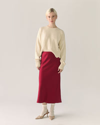 Woman wearing a beige sweater and red pomegranate skirt