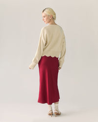 Woman wearing a beige sweater and red pomegranate skirt