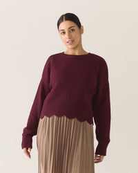 Woman wearing a burgundy zinfandel sweater and mocha brown pleated mesh skirt