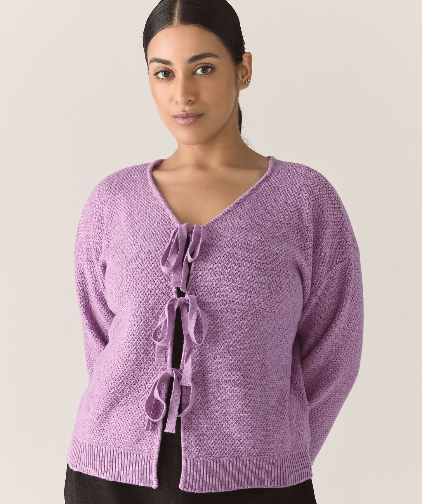 Woman wearing a purple lilac knitted cardigan with a tie bows detail 