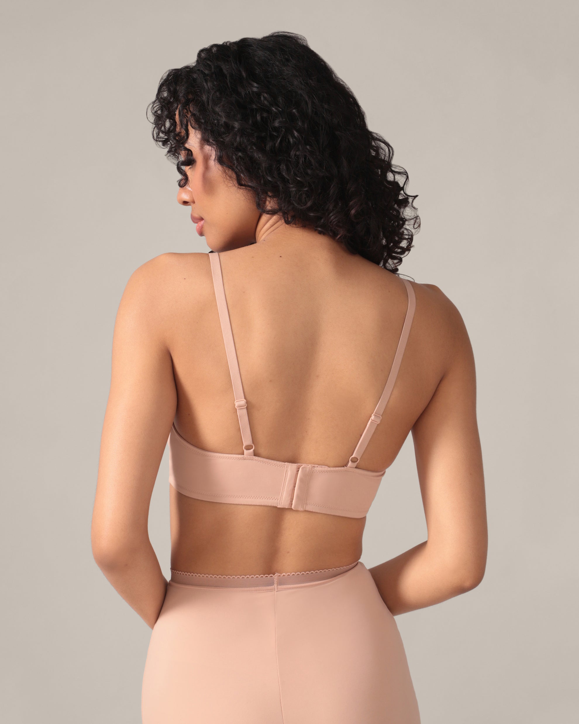 Woman wearing a beige shapewear garment against a neutral background