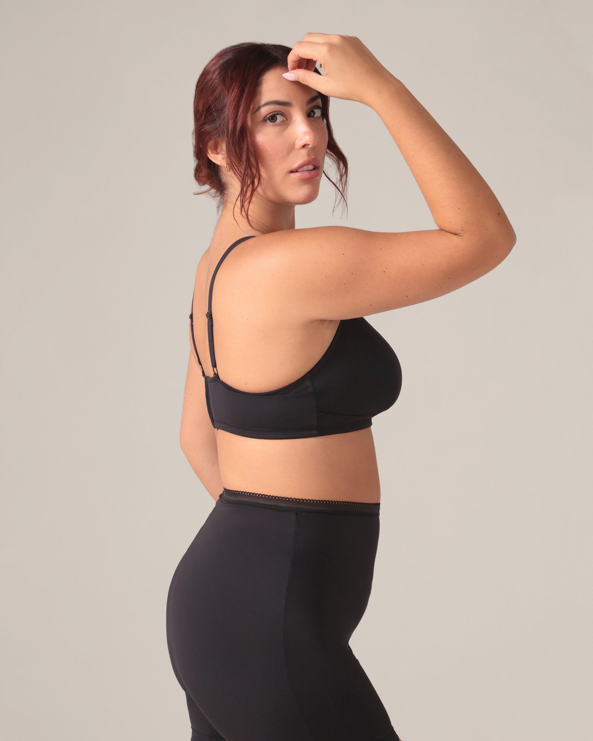 Woman wearing a black bra and anti chaffing shorts against a plain background