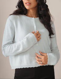 Woman wearing a light blue cardigan against a beige background