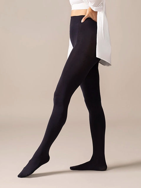 Woman wearing a white blouse and navy tights on a beige background