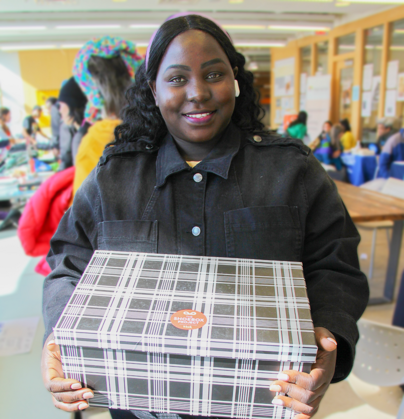 Person holding a plaid box with a visible brand logo in an indoor setting